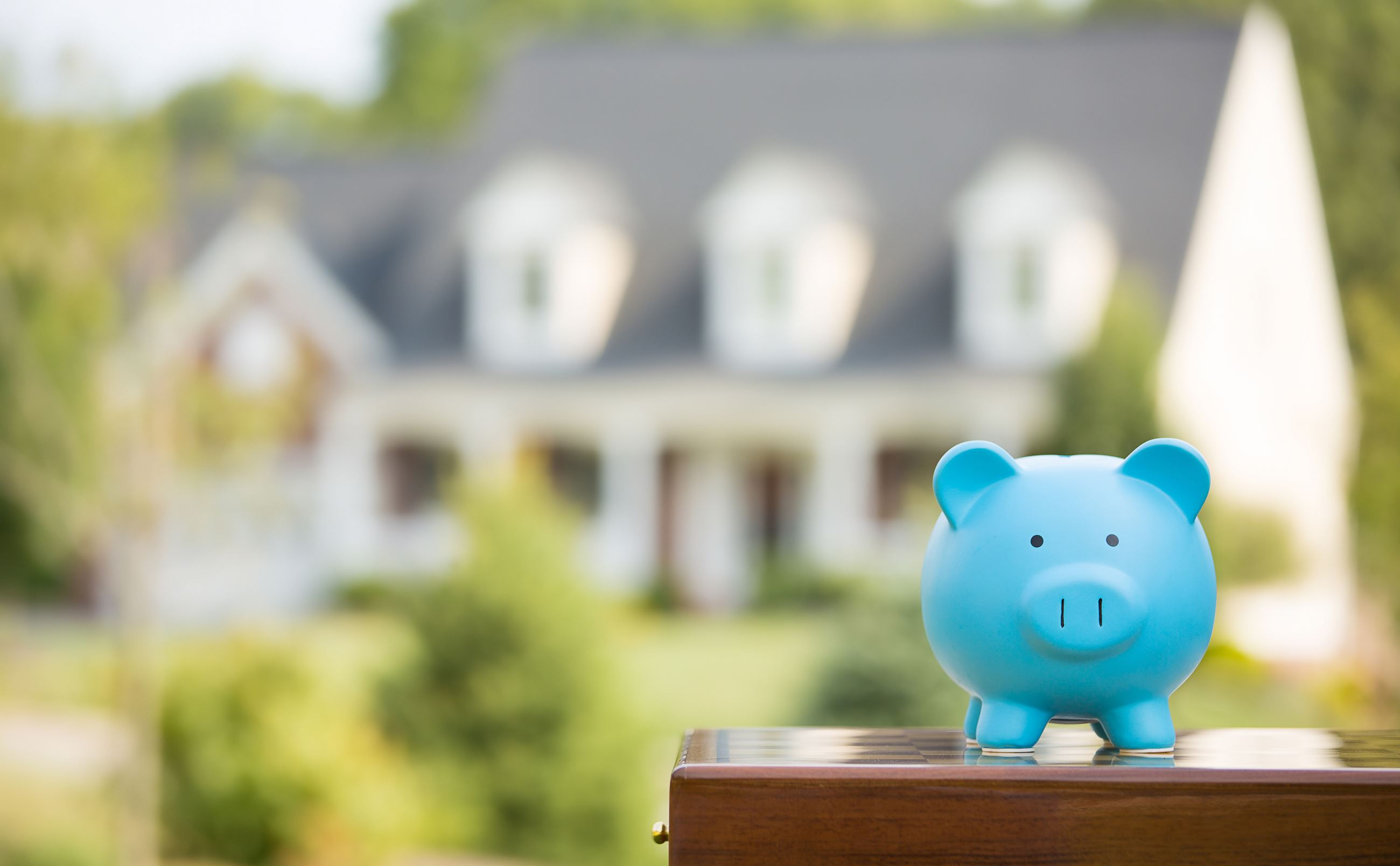 Image of piggy bank with house in background