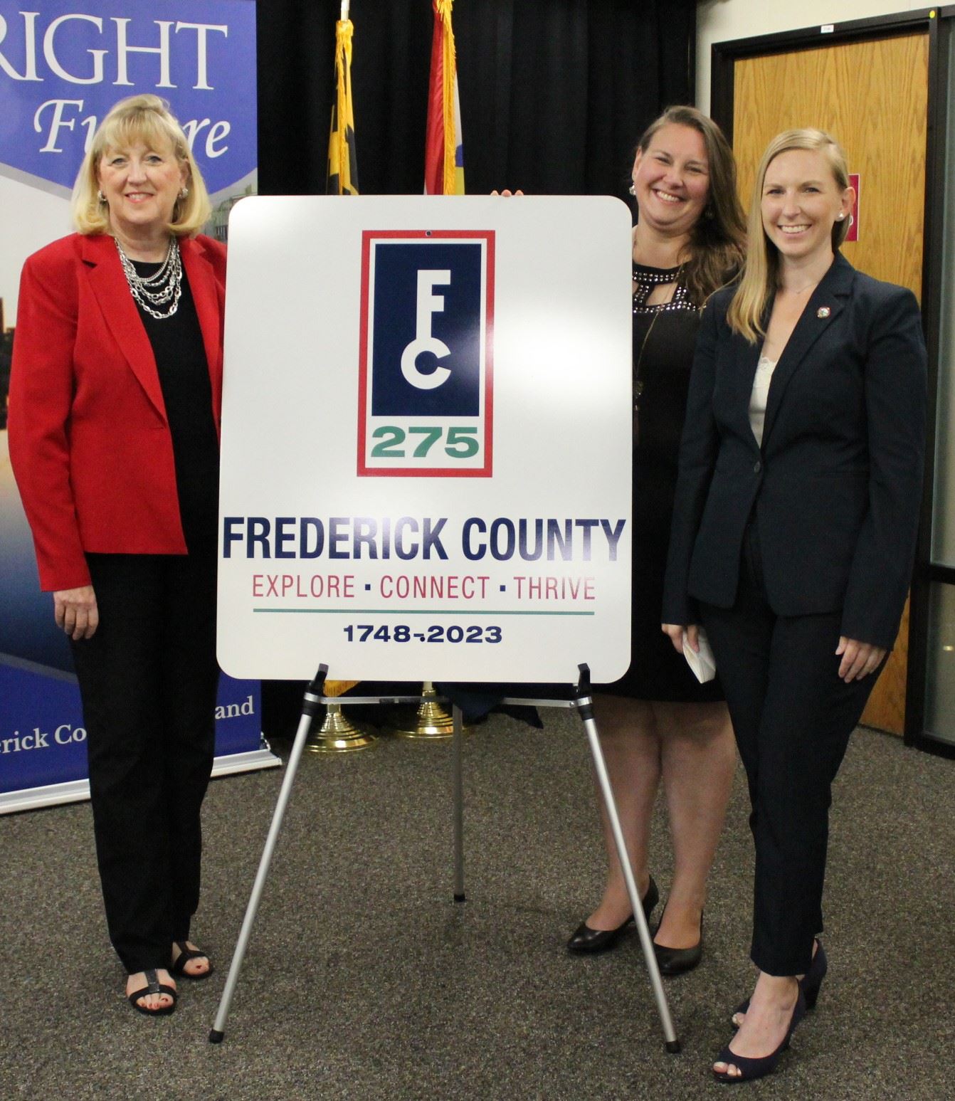 County Executive Jan Gardner, Kari Saavedra and Heidi Keeney stand by a sign showing a key