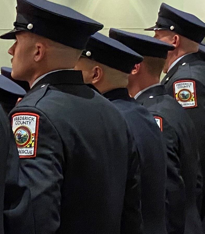 Firefighters in dress uniforms stand in a line