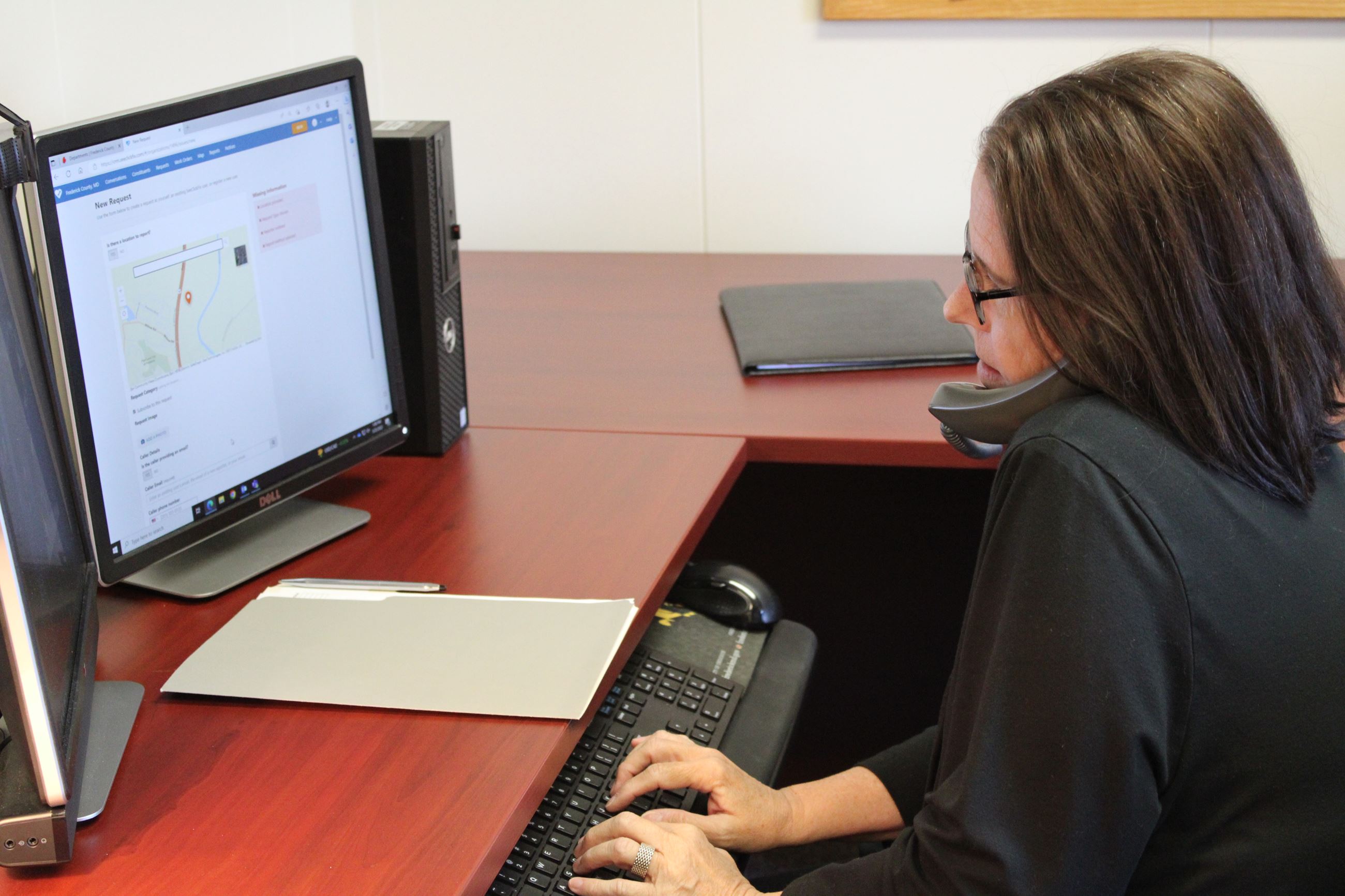 Woman on phone while typing on a computer  keyboard