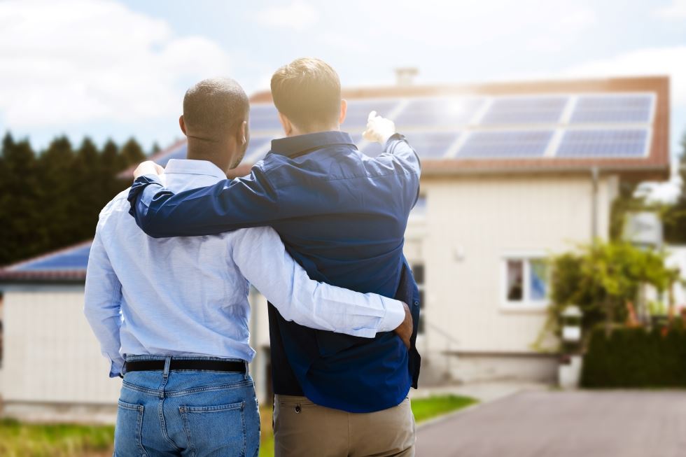 A couple stands looking at their home's solar energy installation