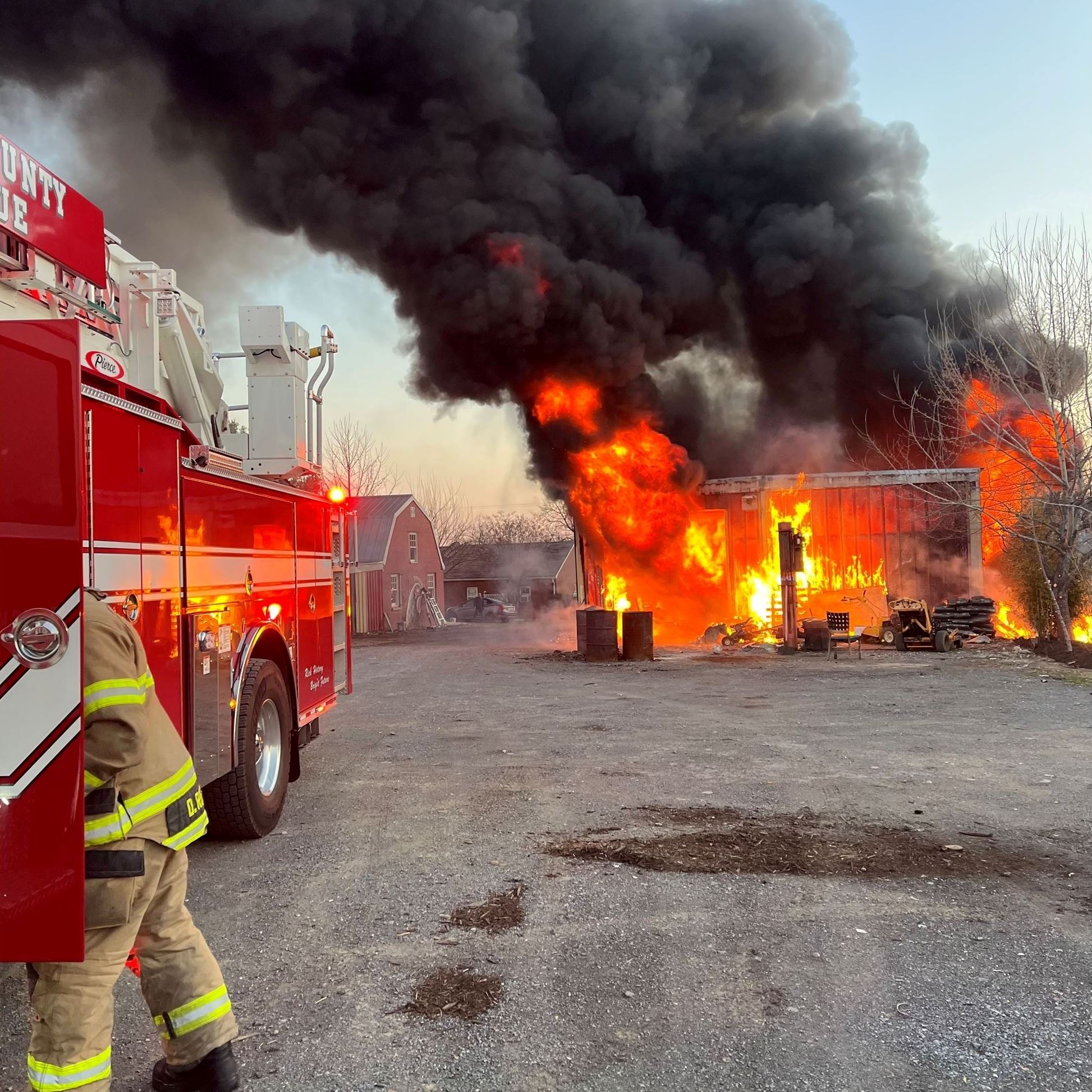 Fire pours out of a barn as firefighters try to extinguish the blaze