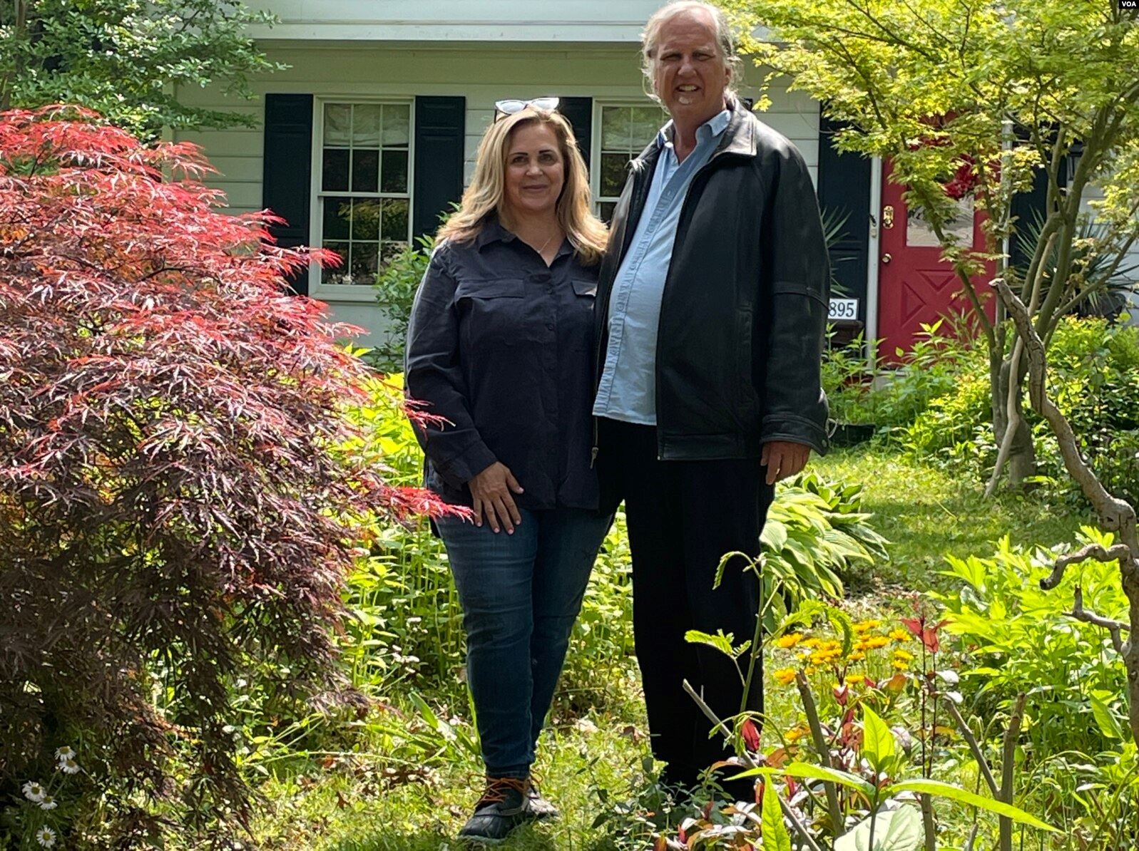Janet and Jeffrey Crouch stand among tall flowers in their yard.