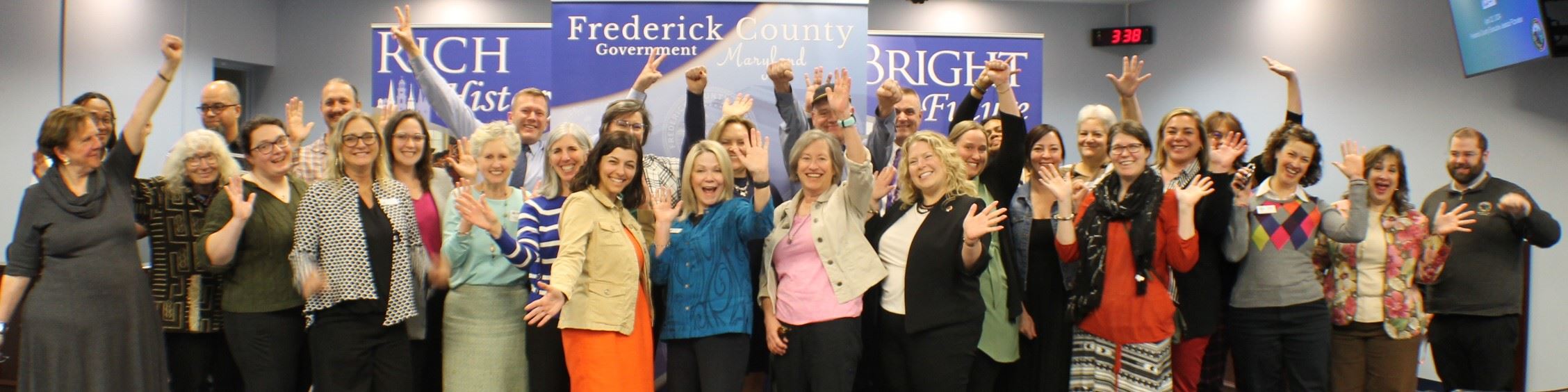 A group of people standing indoors, celebrating with their arms in the air