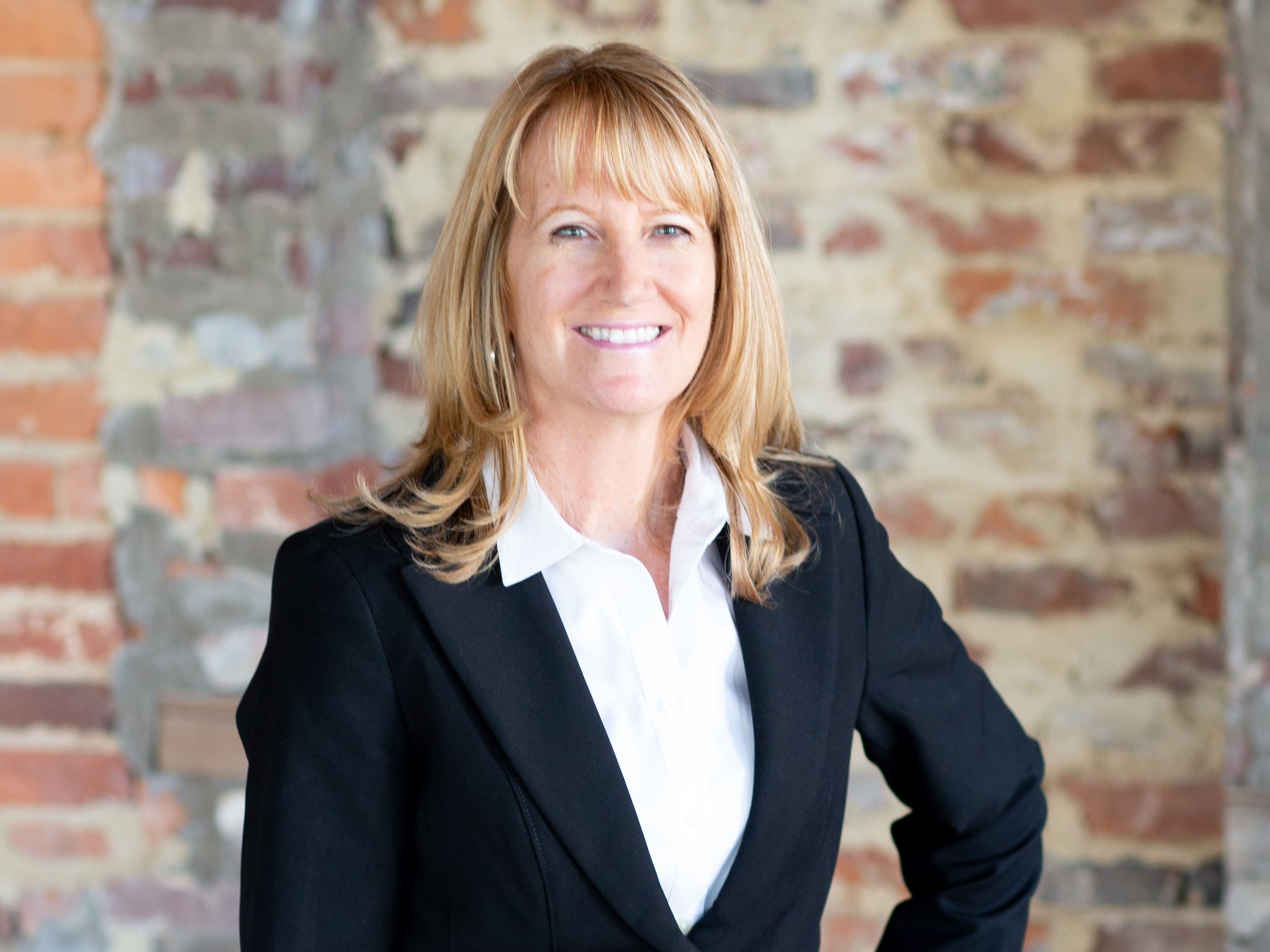 A headshot of a woman in a suit smiling.