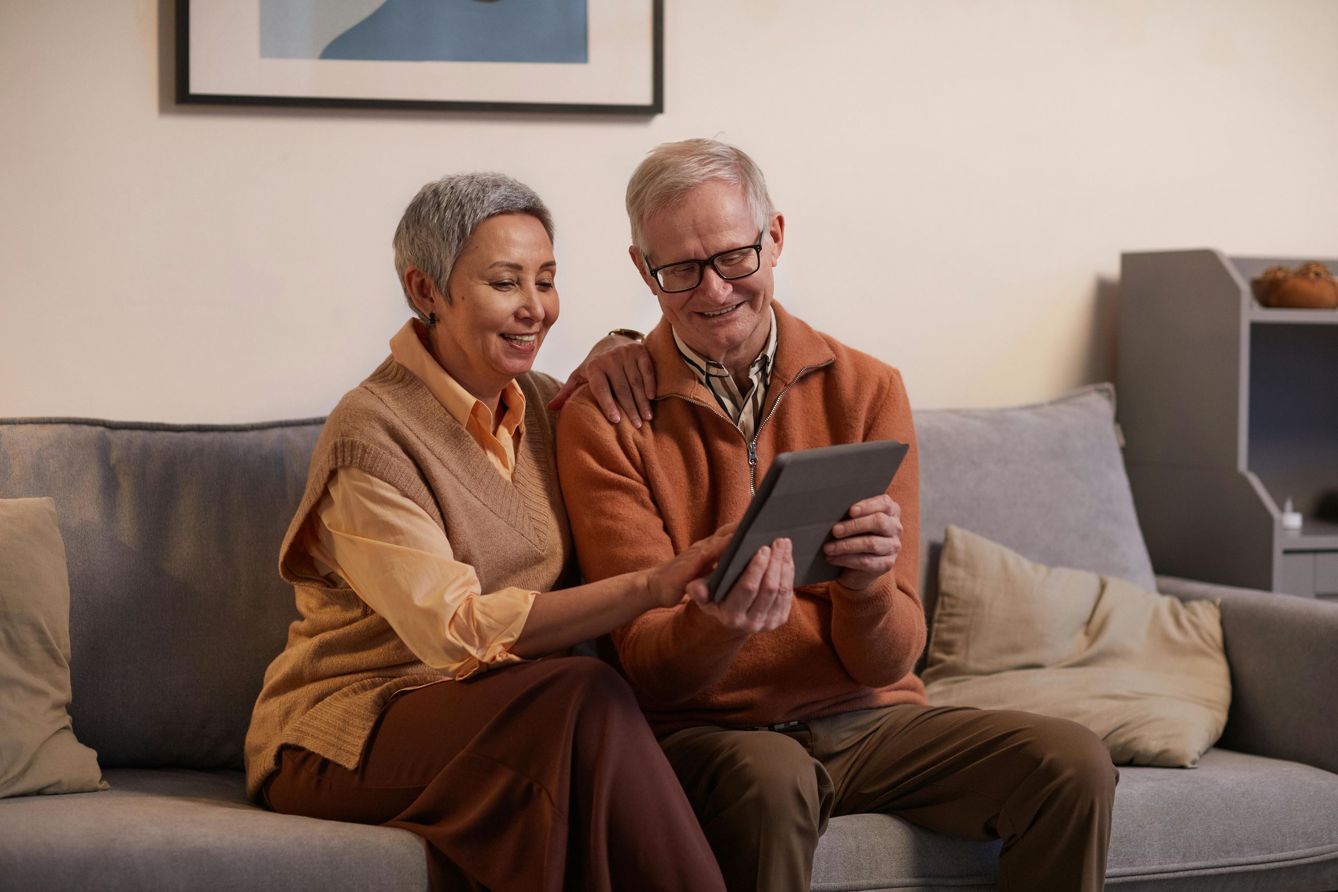 Man and Woman sitting on couch looking at tablet