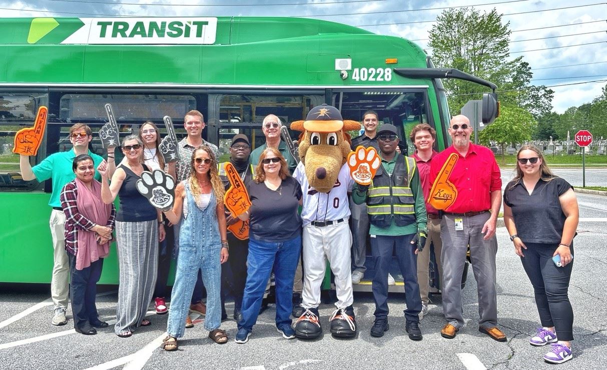 A group of people posing for a photo outside in front of a bus.