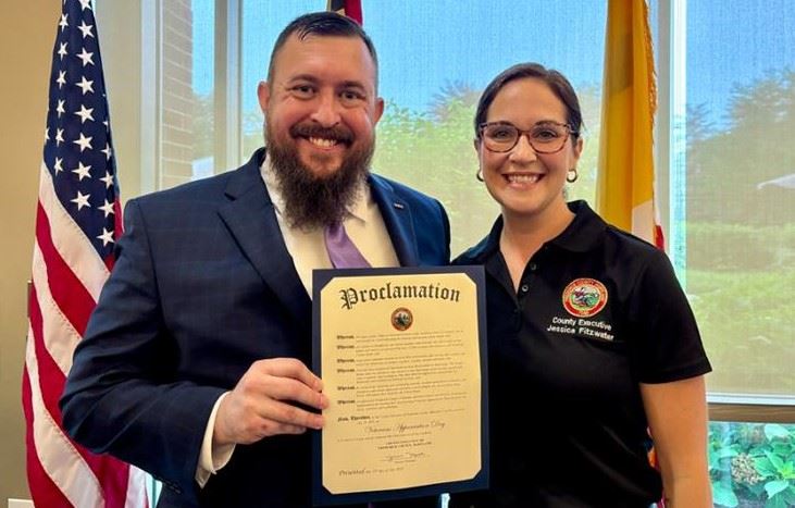Two people posing for a photo, holding a certificate. 