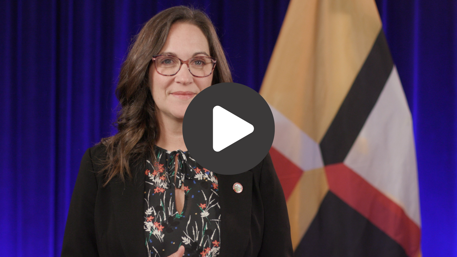 A woman smiling in front of a flag.