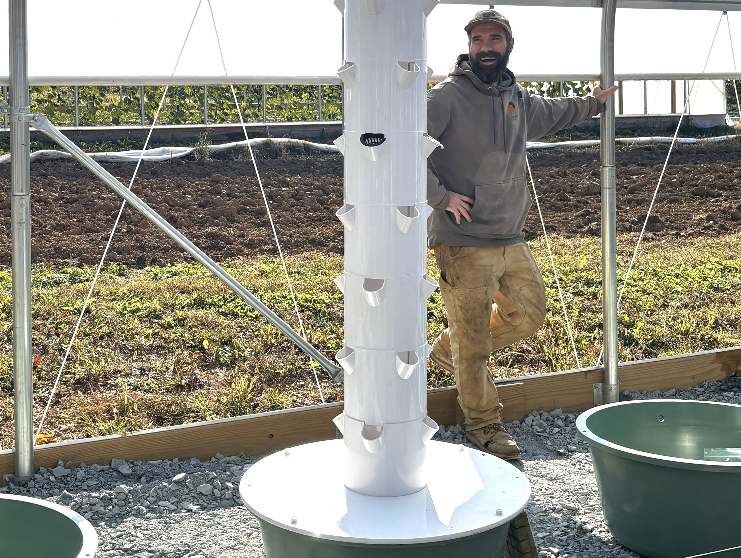 A farmer standing next to a grow tower.